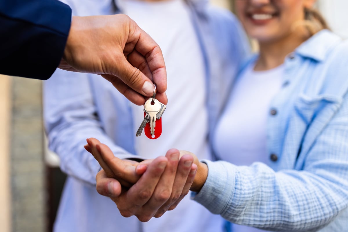 Real estate agent handing over keys to a young couple for their new home